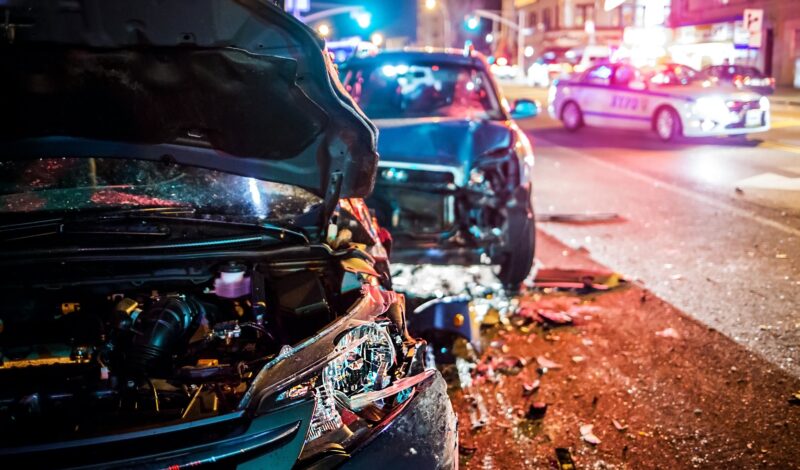 Close-up of a nighttime collision scene with two severely damaged vehicles and police presence, representing the urgency of hiring a car accident attorney.