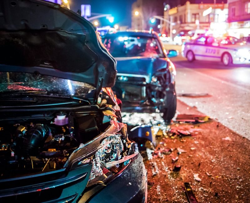 Close-up of a nighttime collision scene with two severely damaged vehicles and police presence, representing the urgency of hiring a car accident attorney.