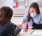Injured woman with a neck brace and arm sling meeting with a female Car Accident Lawyer in a law office, holding hands across a desk during a supportive legal consultation.