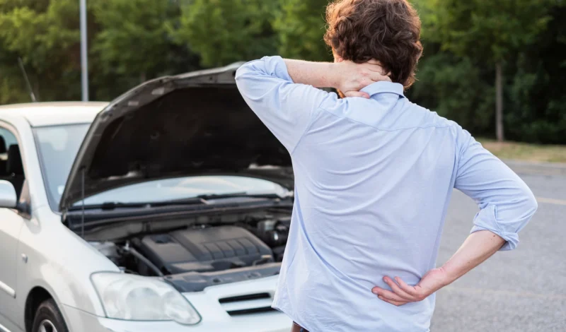 Driver standing beside a disabled vehicle after a crash, highlighting the need to contact a car accident lawyer in Las Vegas for legal guidance.